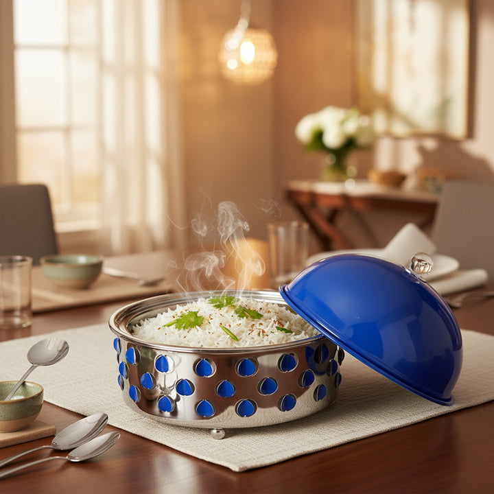 Stainless steel serving dish with blue polka dot pattern on a dining table.