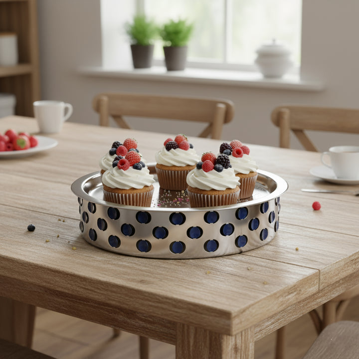 Cupcakes with white frosting and berries on a polka dot tray on a wooden table.