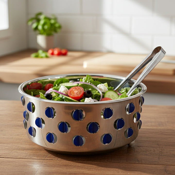 Stainless steel salad bowl with blue polka dot pattern on a wooden table, containing a fresh salad.