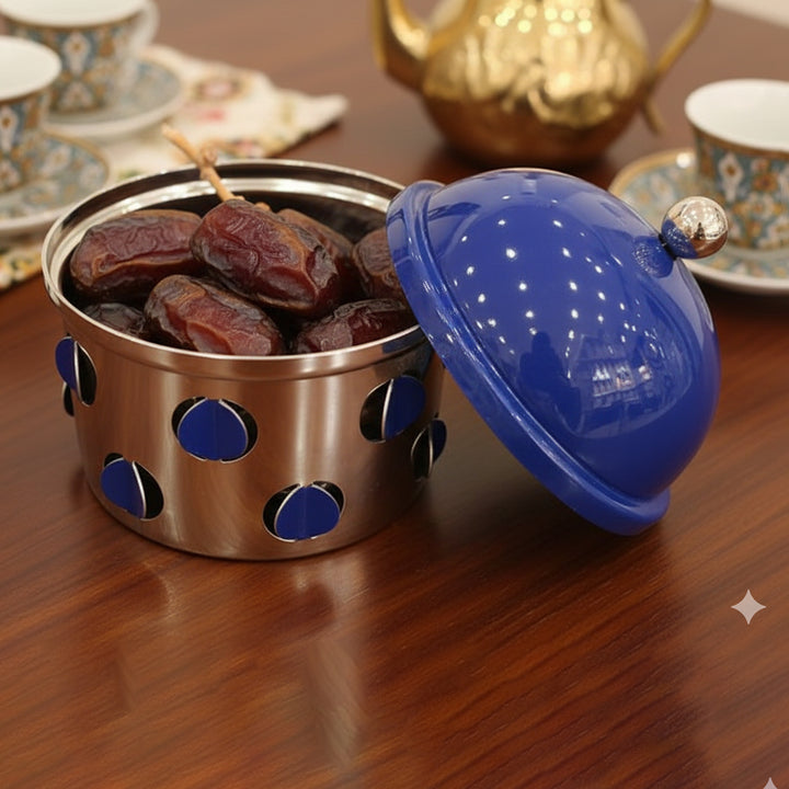 Stainless steel container with blue lid holding dates on a wooden surface