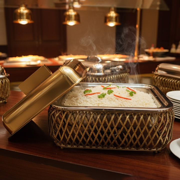 Decorative container with rice and vegetables on a wooden table, with a blurred background of a restaurant setting.