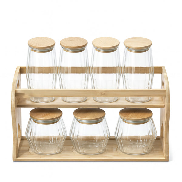 Set of glass jars with wooden lids on a wooden rack against a white background