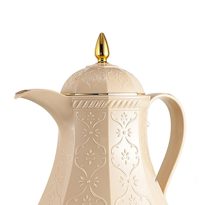 Cream-colored ceramic teapot with gold accents on a white background