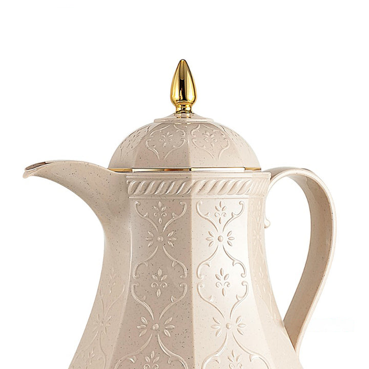 Decorative cream-colored teapot with gold accents on a white background