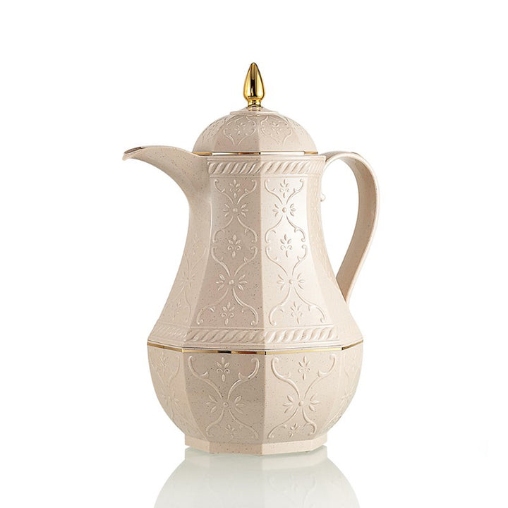 Decorative cream-colored teapot with gold accents on a white background