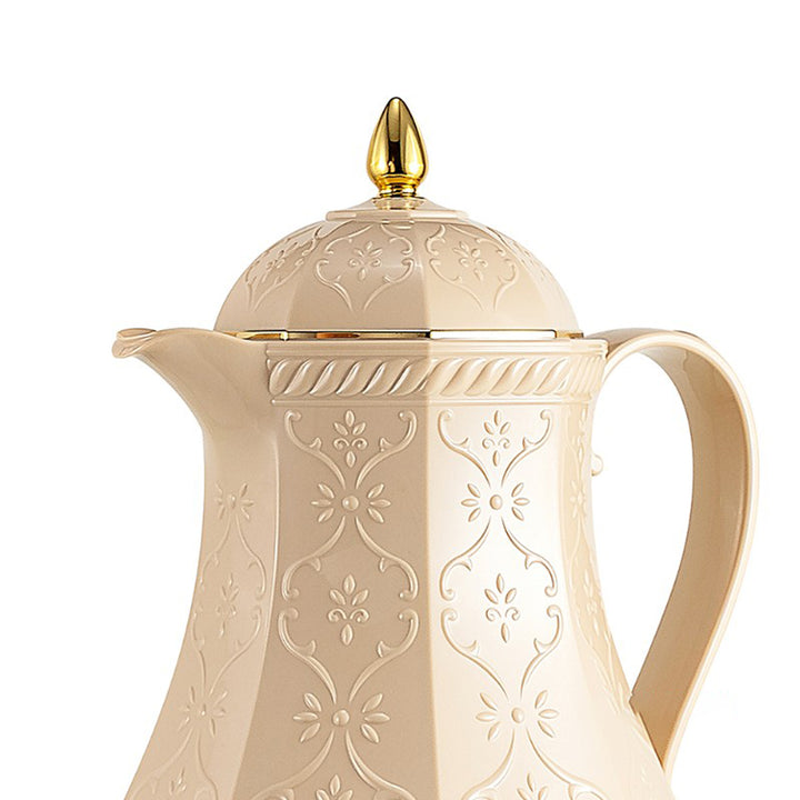 Decorative cream-colored teapot with gold accents on a white background