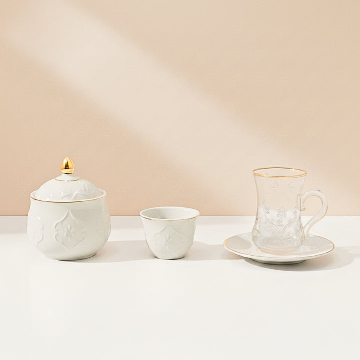 Set of ceramic tea cups and a sugar bowl on a light surface with a beige background