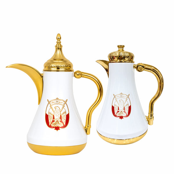 Two white coffee pots with gold accents and red emblem on a white background