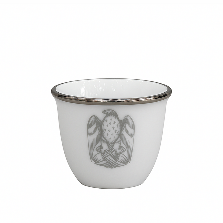 White ceramic cup with a decorative emblem on a white background