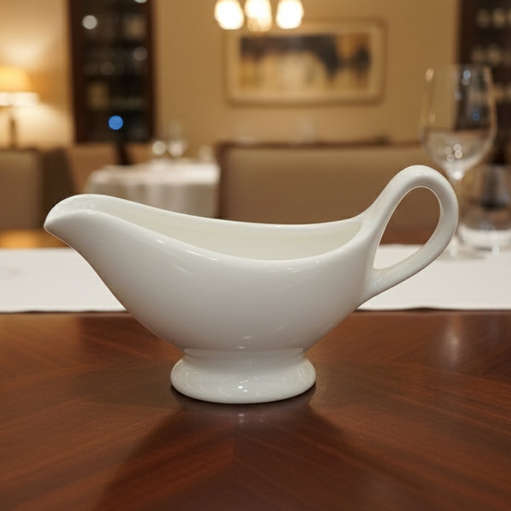 White ceramic gravy boat on a wooden table with a blurred background