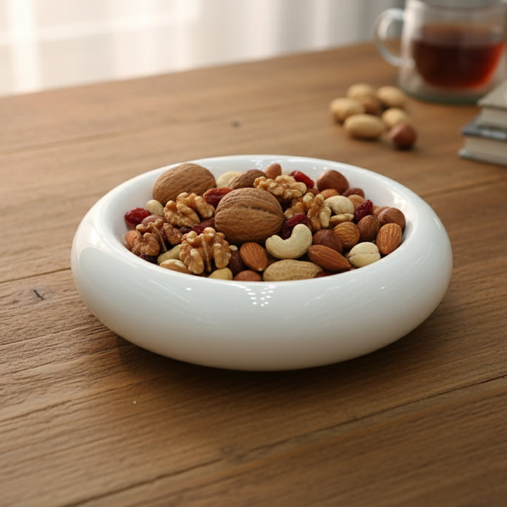 White bowl filled with a mix of nuts on a wooden table
