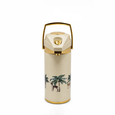 A cream-colored insulated bottle with a gold-tone metal handle and trim, featuring a tropical palm tree and deer illustration on the front.