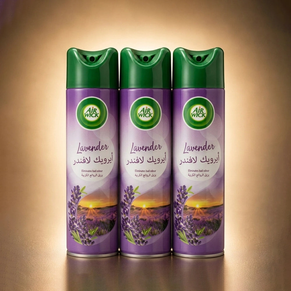Three Air Wick Lavender fresh air spray cans lined up side by side on a warm, golden-brown gradient background. The cans are purple with green caps and feature a lavender field sunset graphic on the label.