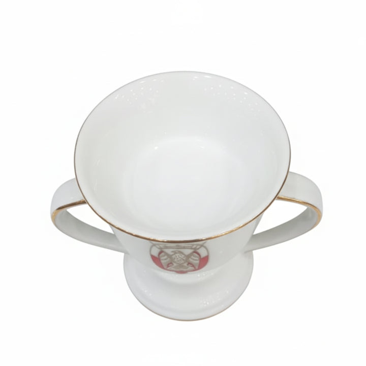 White ceramic cup with gold rim and a visible brand logo on a white background