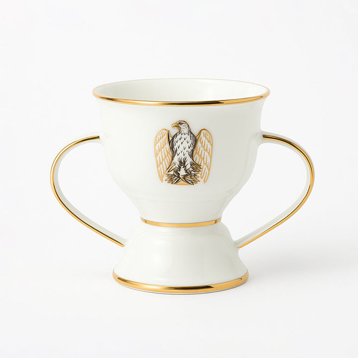 White ceramic cup with gold accents and an eagle emblem on a white background