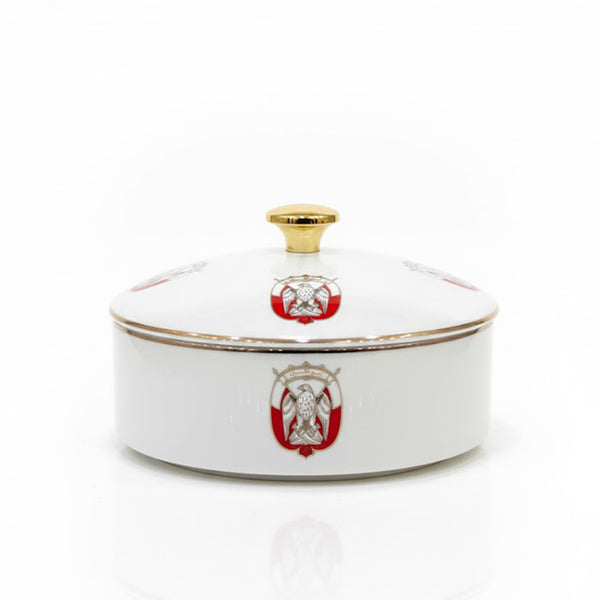 White ceramic dish with gold rim and red emblem on a white background