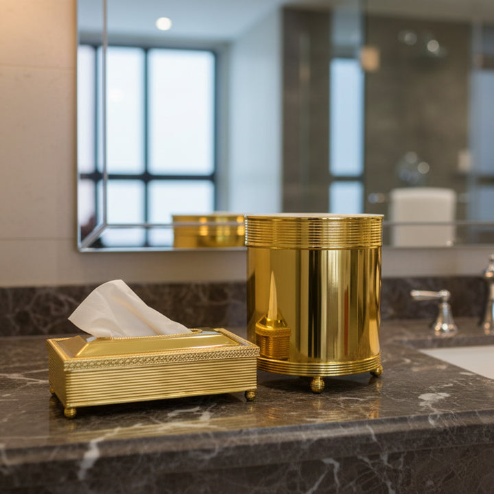 Gold tissue box and trash can on a bathroom counter with blurred background