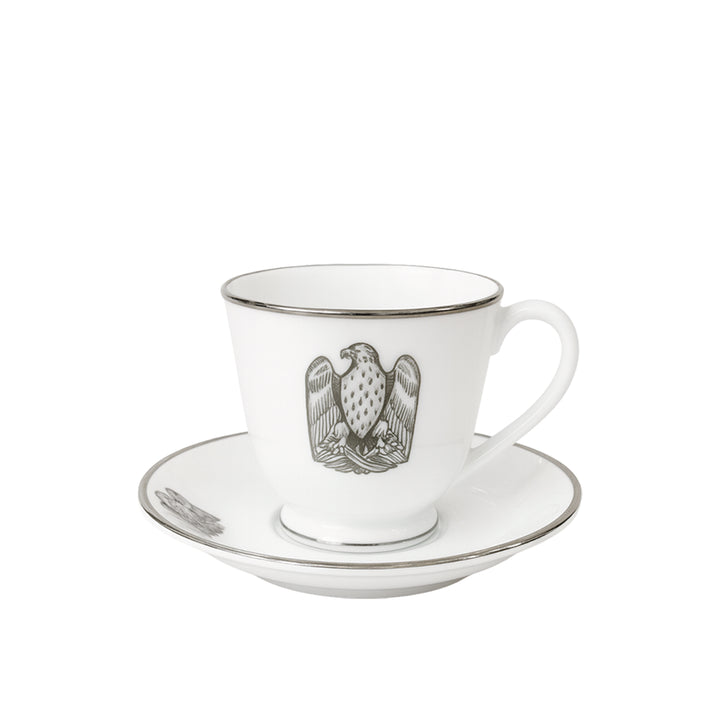 White teacup and saucer with an eagle emblem on a white background