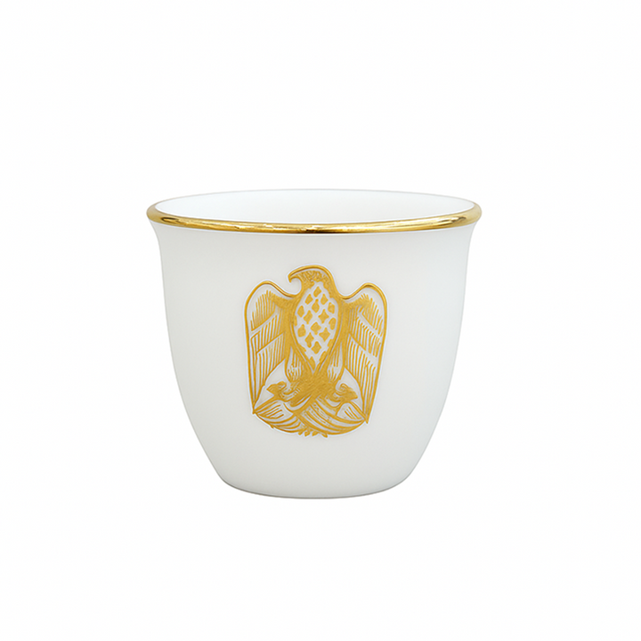 White cup with gold rim and eagle emblem on a white background