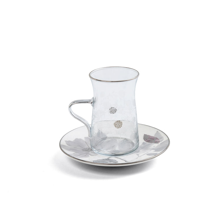 Clear glass cup and saucer set on a white background