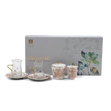 Tea set with floral design in front of a decorative box on a white background