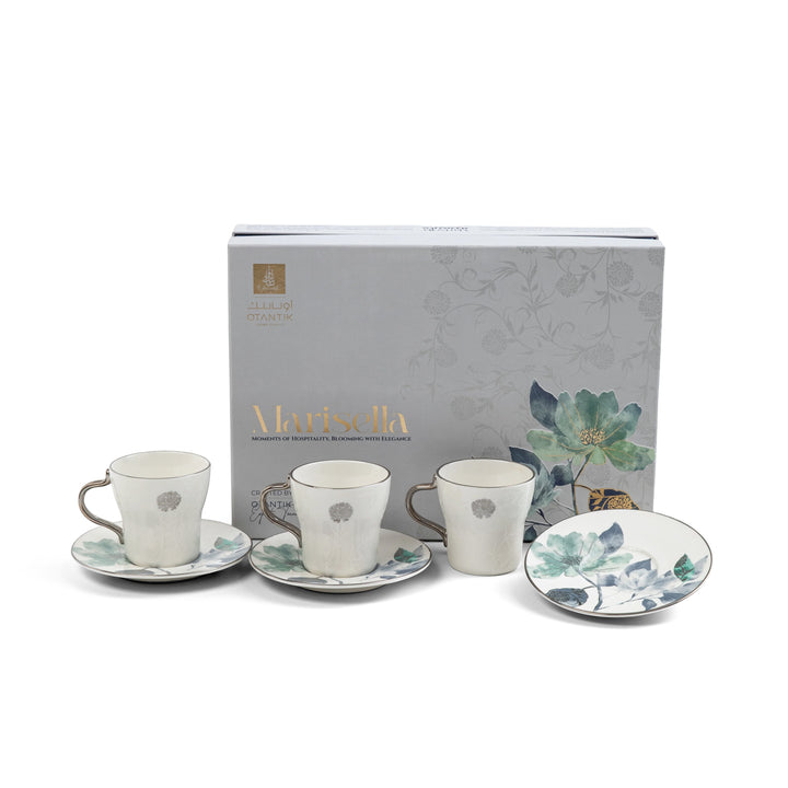 Set of ceramic tea cups and saucers with floral design in front of a branded box on a white background
