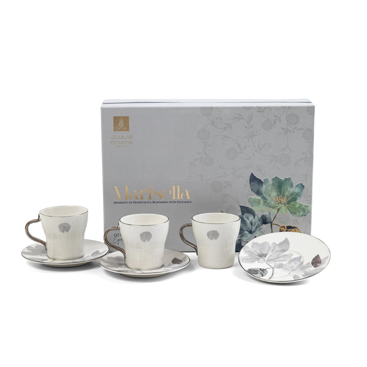 Set of ceramic cups and saucers with floral design in front of a Marisella branded box.