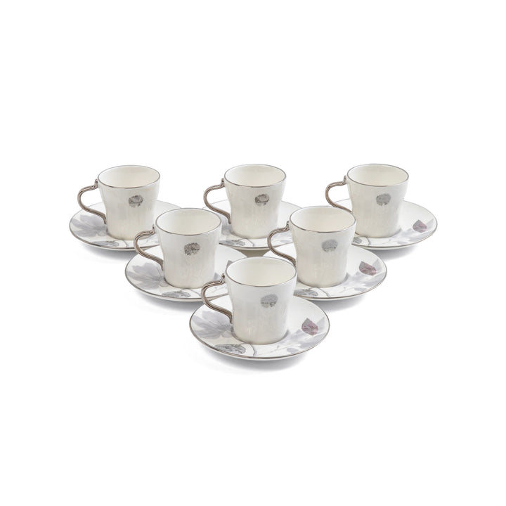 Set of six white ceramic espresso cups and saucers with decorative elements on a white background