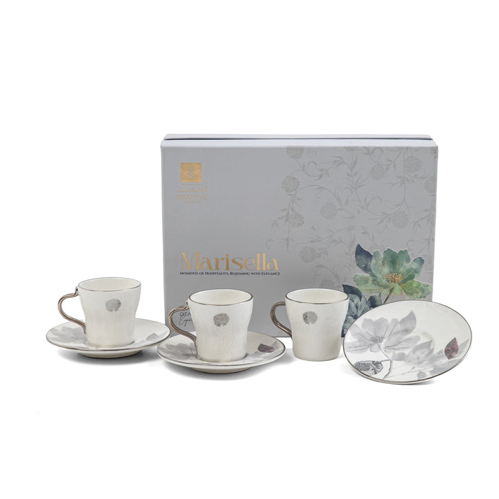 Ceramic tea set with saucers and coasters in front of a branded box on a white background