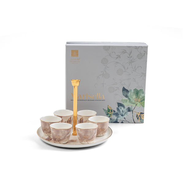 Set of ceramic cups with a gold handle on a white plate, next to a decorative box with floral designs.