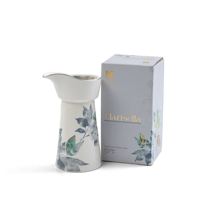 White ceramic pitcher with floral design next to its packaging box on a white background