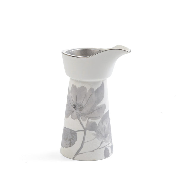 White ceramic creamer with floral design on a white background