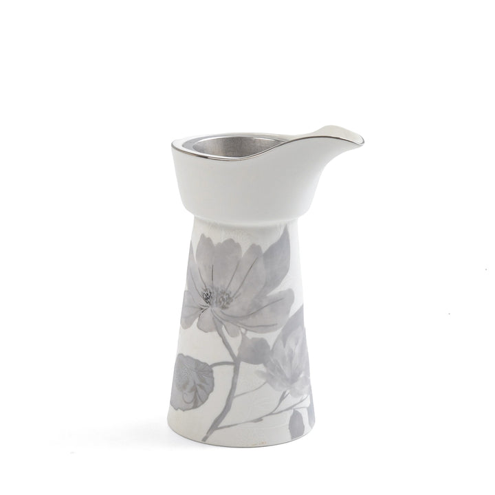 White ceramic creamer with floral design on a white background