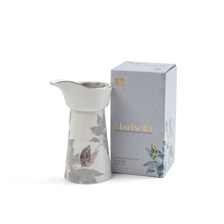 White ceramic pitcher with floral design next to its packaging box on a white background