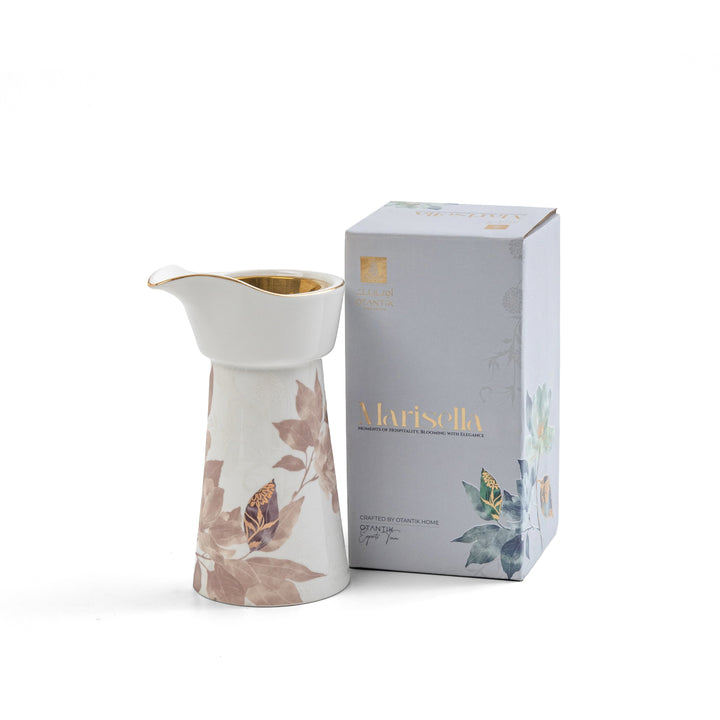 White ceramic pitcher with floral design next to a branded box on a white background