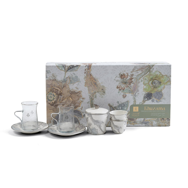 Tea set with four cups and saucers in front of a floral-patterned box on a white background