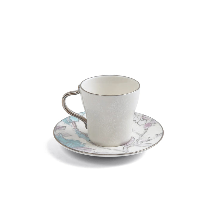 White ceramic cup and saucer with floral design on a white background