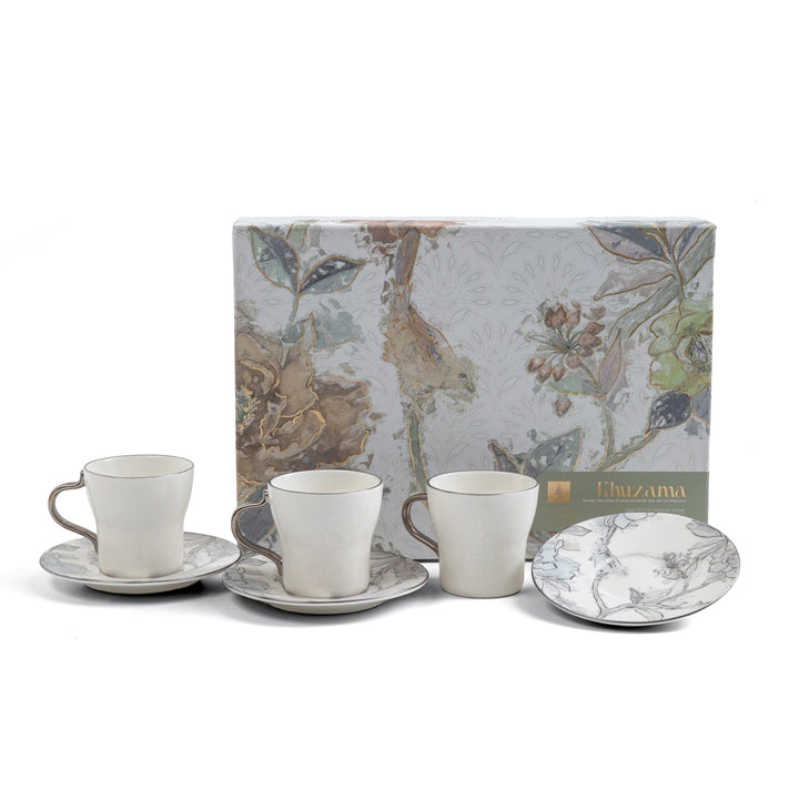 Set of ceramic cups and saucers with a decorative box in the background