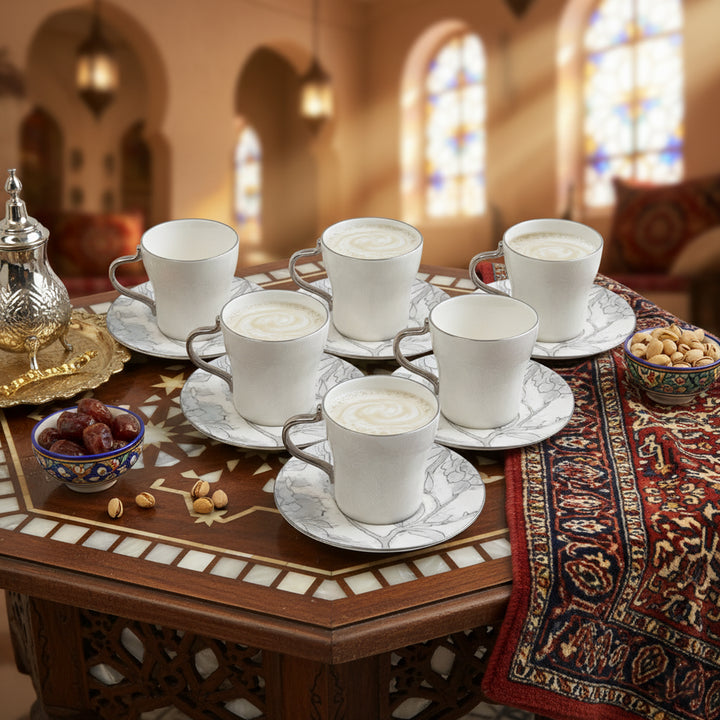 Café au lait served in white cups on a decorative table with a warm, blurred background.
