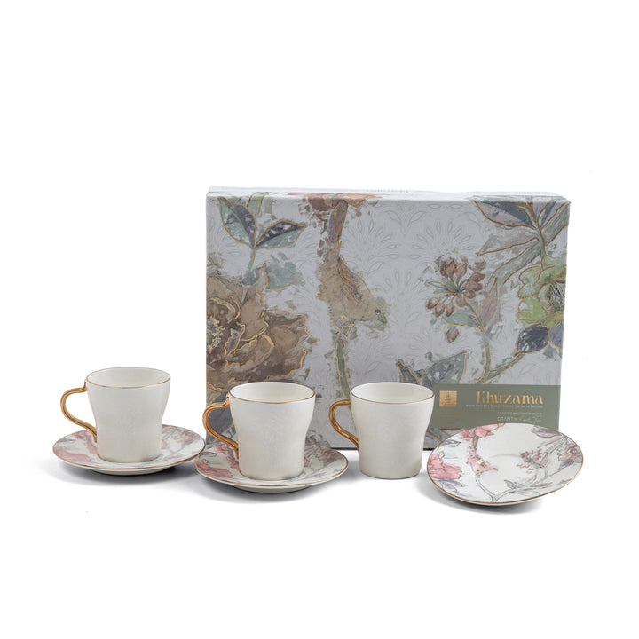 Set of ceramic tea cups and saucers with a decorative box in the background