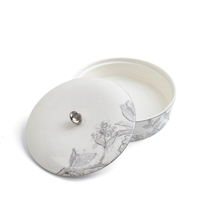 Round silver jewelry box with floral design on a white background