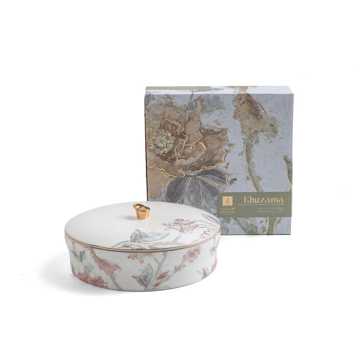 Decorative ceramic container with floral design and matching box on a white background
