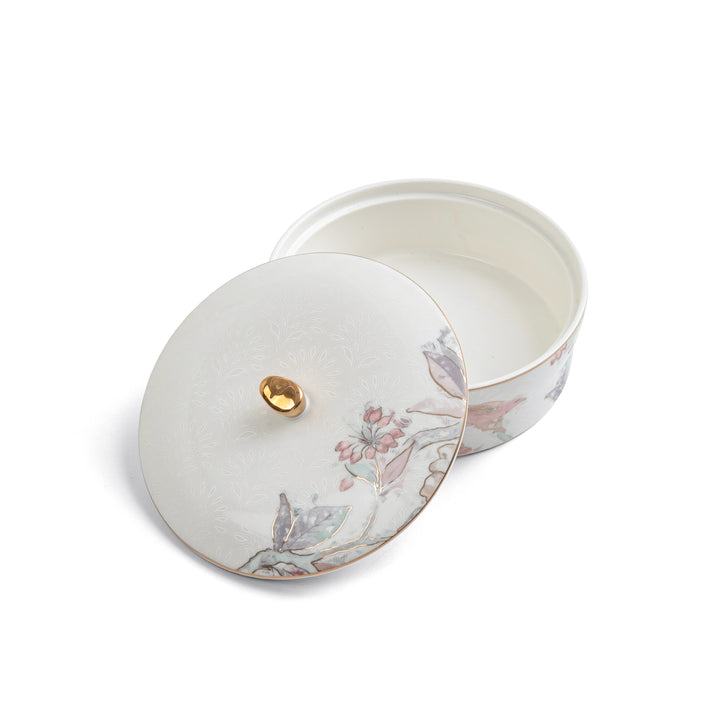 Round ceramic tin with floral design and gold accent on a white background