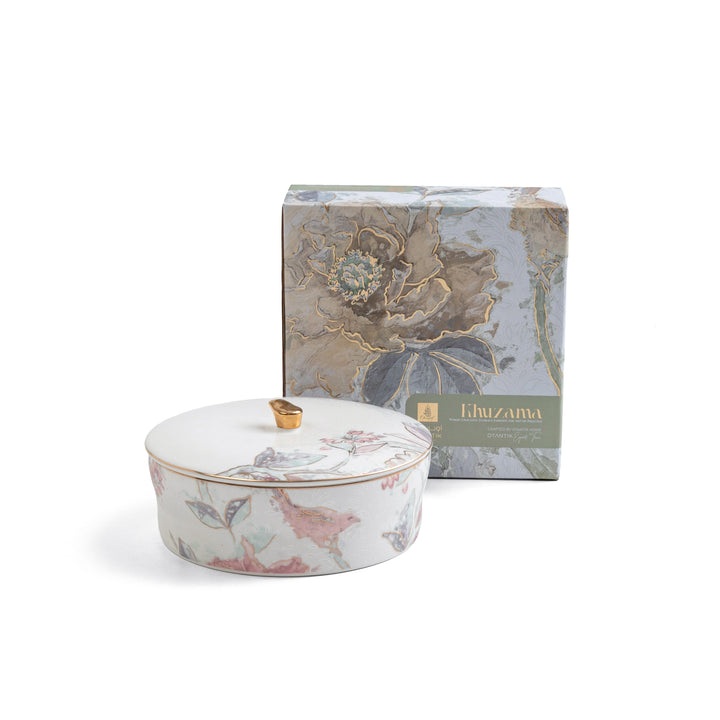 Decorative ceramic lidded container with floral design in front of a matching box on a white background