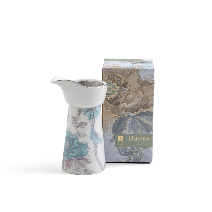 Ceramic pitcher with floral design next to a branded box on a white background