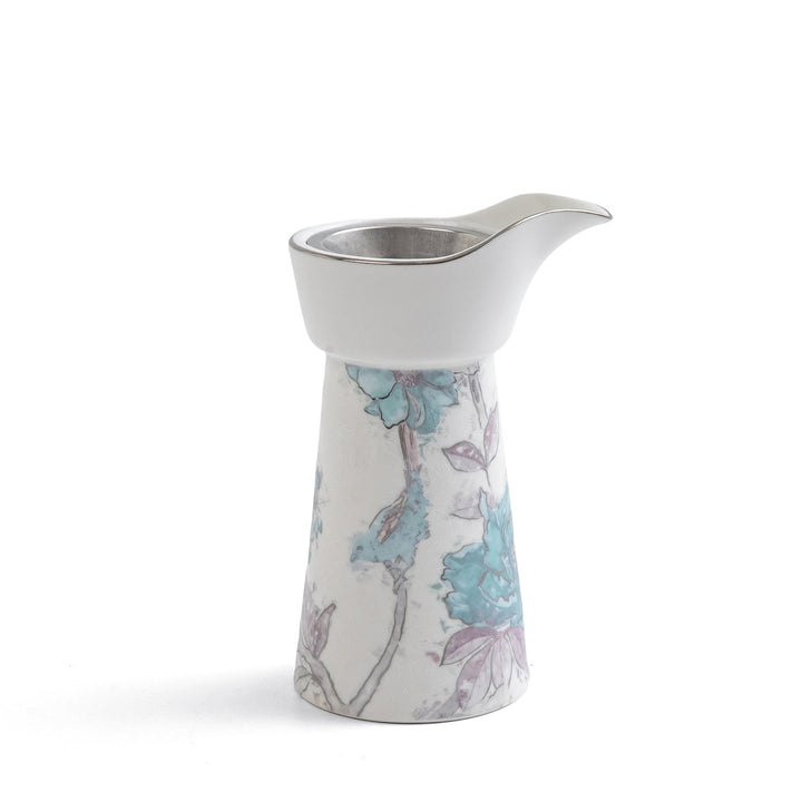 Ceramic creamer with floral design on a white background