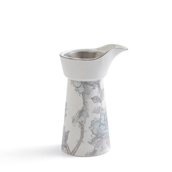 White ceramic creamer with floral pattern on a white background