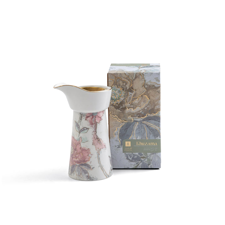 Decorative ceramic pitcher with floral design next to its packaging box on a white background