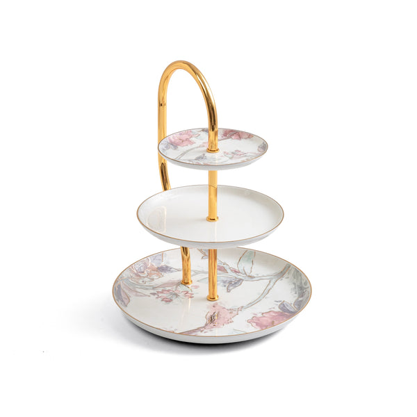 Three-tiered ceramic cake stand with floral design and gold accents on a white background
