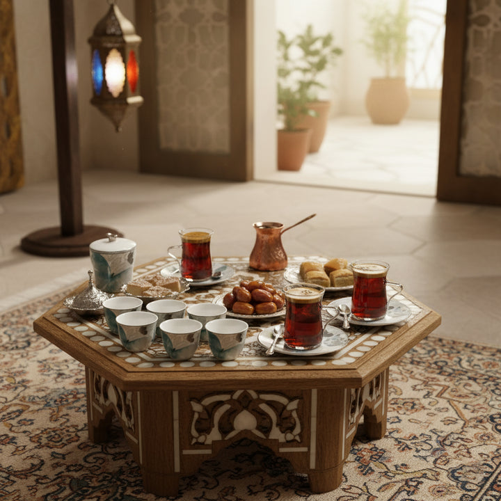 Tea set with cups and a teapot on an ornate wooden table in a room with plants and a lantern.